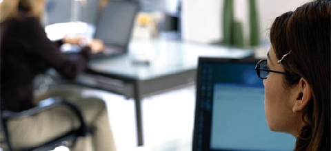 Image of two professional office workers on laptops